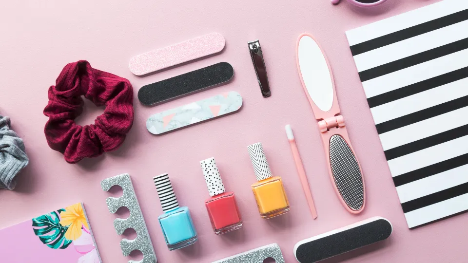 Nagellakjes en kleine verzorgingsartikelen op een roze vlak
