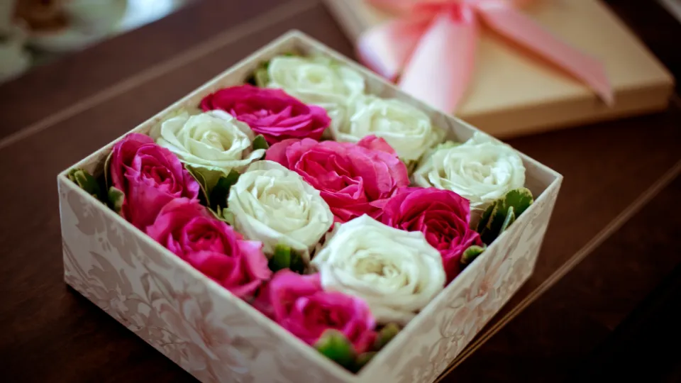 Doos met roze en witte rozen op een houten tafelblad